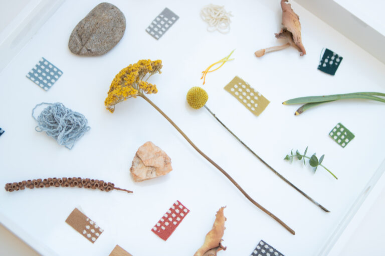A palette of fabric cuttings and natural objects such as stones and dried flowers.