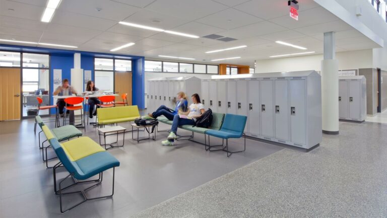 School lounge seating next to a row of lockers, and students reading.