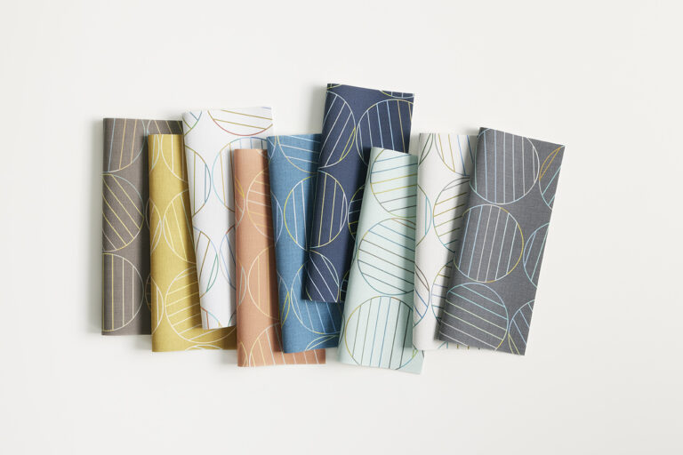 A row of textile samples in various colors that has a pattern of large circles filled with lines.