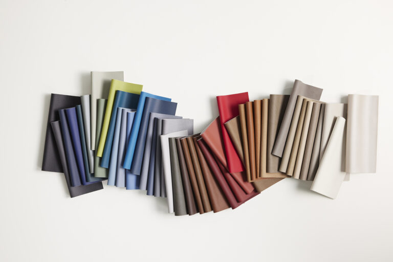 A row of samples of coated textiles in various colors on a white background.